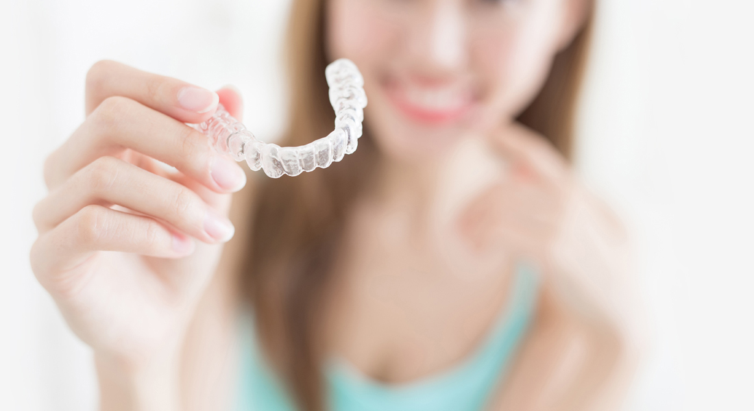 Woman holding Invisalign clear aligner
